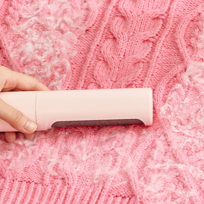 Using reusable pet hair remover roller on pink sweater